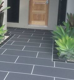 the front entrance of a house with plants and potted plants