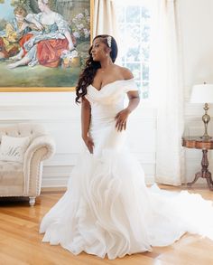 a woman in a white wedding dress posing for the camera with her hands on her hips