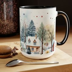 a coffee mug sitting on top of a wooden table next to a spoon and cookie