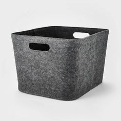 a large gray storage basket with handles on the front and bottom, sitting against a white background