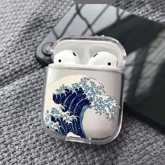 an airpods case with the great wave on it is sitting on top of a table