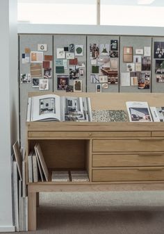 a wooden desk with many pictures on the wall behind it and bookshelf below