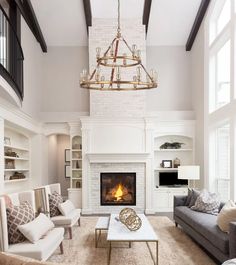 a living room filled with furniture and a fire place under a chandelier hanging from the ceiling