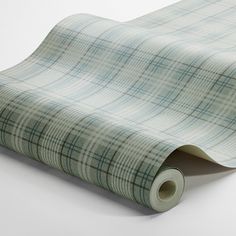 a green and white checkered wallpaper with a rolled up roll on the floor