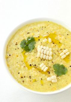 a white bowl filled with soup and garnished with corn kernels on top