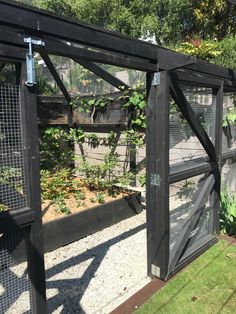 an open gate in the middle of a garden with lots of plants growing inside it