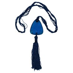 a blue necklace with tassels and beads hanging from it's side on a white background