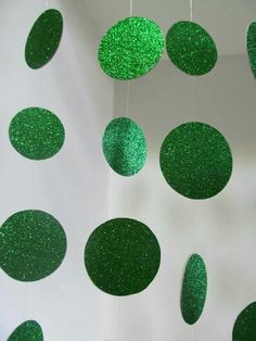 green glitter circles hanging from the ceiling in front of a white wall with black dots