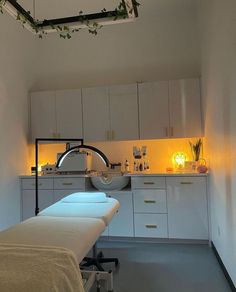 a treatment room with two beds and lights on the wall above them, in front of white cabinets