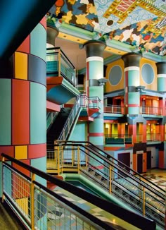 the interior of a multi - colored building with stairs and railings painted in different colors