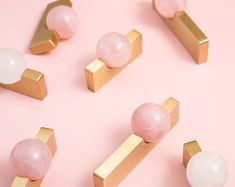 several pink and white marble knobs on gold colored metal handles against a pale pink background