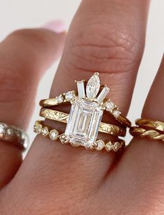 a woman's hand with three different rings on it and an emerald stone in the middle