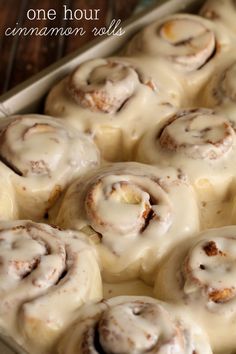 glazed cinnamon rolls in a baking pan on a cooling rack with the words, one hour cinnamon rolls