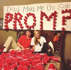 two people sitting on a bed with red cups in front of them and a sign that says don't make me go solo