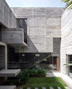 an outdoor courtyard with grass and stairs leading up to the second floor, surrounded by concrete blocks