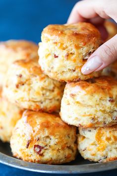 a hand picking up some biscuits from a plate