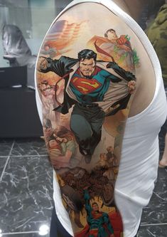 the back of a man's arm with superman tattoos and other artwork on it