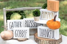 three wooden blocks with words on them sitting on top of a table next to pumpkins