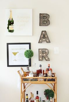 a bar cart with liquor bottles on it in front of two framed letters that spell out the word bar