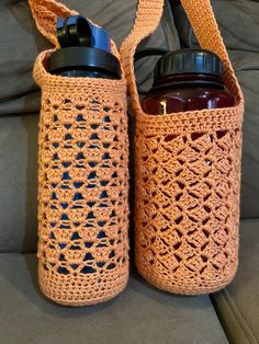 two crocheted water bottles sitting next to each other on a couch in front of a pillow