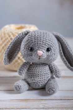 a gray crocheted bunny sitting next to a bag