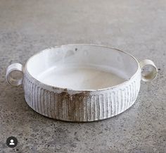 a white bowl sitting on top of a cement floor