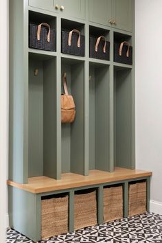 an empty bench with baskets on it in front of a coat rack and storage bins