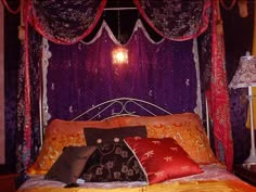 a bed with purple curtains and pillows on it