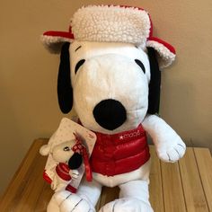 a white stuffed dog with a red bandanna on it's head sitting on a wooden table