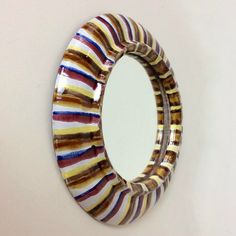 a circular mirror mounted to the side of a wall next to a white wall with stripes on it