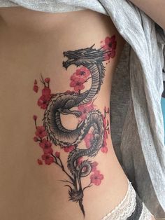 a woman with a tattoo on her stomach has a dragon and flowers in the shape of a heart