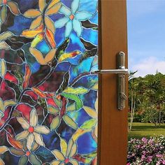 an open door to a garden with colorful flowers and trees in the backround