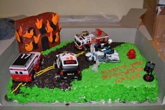 a birthday cake with cars and fire trucks on the top is decorated in green frosting