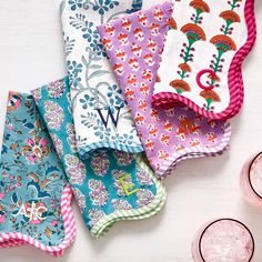 five colorful cloths are laid out on a table next to some glasses and cups