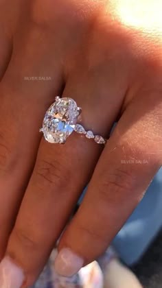 a woman's hand with an oval diamond ring on it, and the middle finger is