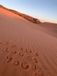 the word jesus loves you written in the sand