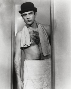 an old photo of a man with a towel around his neck and shirtless torso