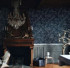 a living room with a fireplace, chandelier and wall papered in blue