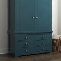 a blue armoire with two drawers and a basket on the floor next to it