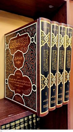 four books on a shelf with arabic writing