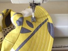 the sewing machine is working on the yellow and gray material that has been stitched together