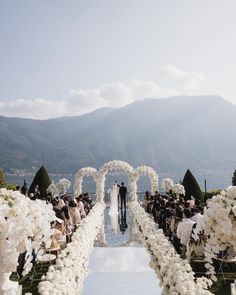 an outdoor wedding ceremony with white flowers and greenery on the aisle, overlooking mountains