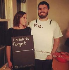 a man and woman standing next to each other holding signs that say i drink to forget