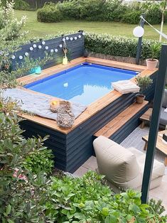 an above ground pool surrounded by greenery and patio furniture in a back yard area