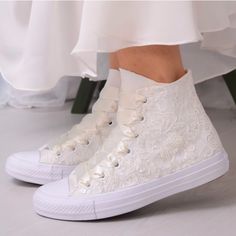 a woman's white high top sneakers with lace and pearls on the bottom,