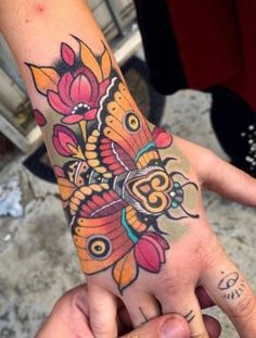 a person's hand with a butterfly tattoo on it and flowers around the wrist