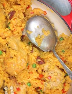 a bowl filled with rice and meat next to a spoon on top of a table