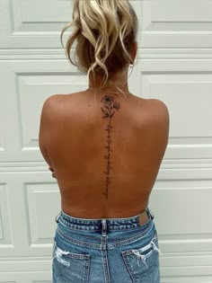 the back of a woman's body with flowers tattooed on her upper and lower back