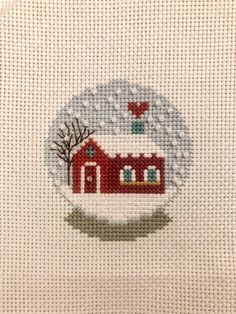 a cross stitch pattern with a red house in the middle and trees on it's side