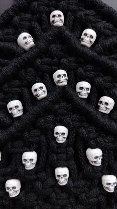 several skulls are arranged in the middle of a knitted black blanket with white faces on them